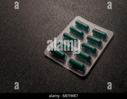 Comprimés vert en blister sur la surface en plastique. Les comprimés de la plaque sur le bureau noir. Blister avec green pills Banque D'Images