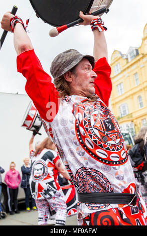 Llandudno, Nord du Pays de Galles- 29 avril 2017 : Les artistes interprètes ou exécutants de la Mersey Batala bande de carnaval à Llandudno. L'homme à chapeau fedora trilby jouant sur un tambour soulever Banque D'Images