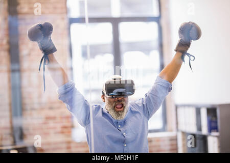 Portrait of businessman avec des lunettes de réalité virtuelle et des gants de boxe dans l'office Banque D'Images