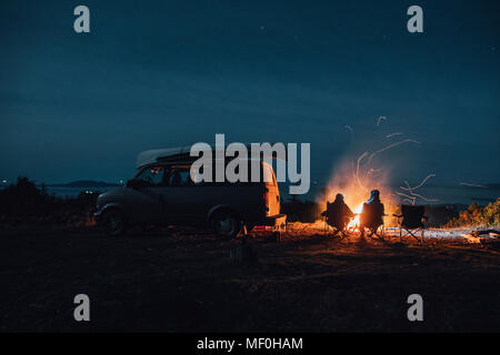 Le Canada, la Colombie-Britannique, Prince Rupert, deux hommes assis devant un feu de camp à la fourgonnette de nuit Banque D'Images