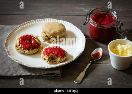 Des scones faits de eingrain avec confiture de fraise et crème caillée Banque D'Images