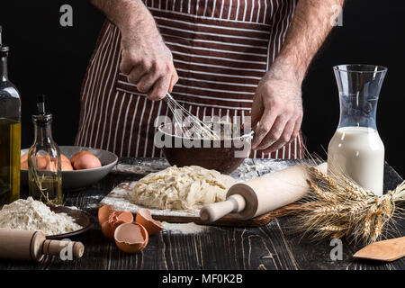 Fouetter les œufs Male chef dans la boulangerie sur table en bois. Ingrédients pour la cuisson des produits de la farine ou de la pâte Banque D'Images