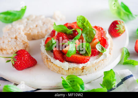 Collation santé avec des fraises fraîches, pain, fromage de chèvre, et les feuilles de basilic. Entrée facile recette. Banque D'Images