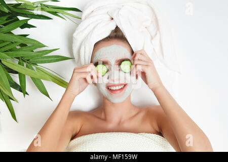 Portrait de femme beauté portant avec une serviette sur la tête, de concombre sur les yeux, masque du visage. La thérapie de Spa. Vous pourrez vous détendre. Fond blanc Banque D'Images