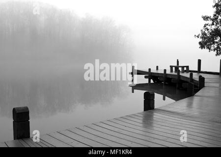 Brouillard recouvre un lac et terrasse en bois sur une morne journée d'hiver. Banque D'Images