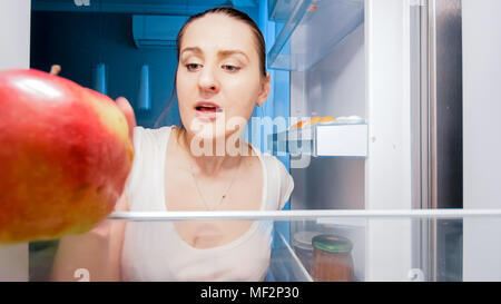 Image Gros plan femme faim de jeunes à la recherche de quelque chose à manger dans le réfrigérateur pendant la nuit Banque D'Images