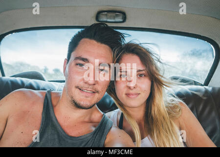 Cuba, jeune couple assis dans une voiture d'époque, en tenant un selfies Banque D'Images