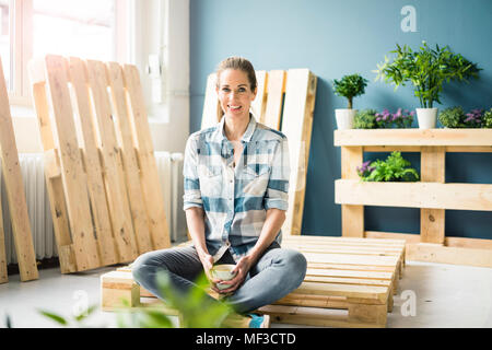 Belle femme prendre une pause pour la rénovation de sa maison avec des palettes, boire du café Banque D'Images