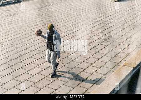 Jeune homme avec le basket-ball marche sur un carré Banque D'Images