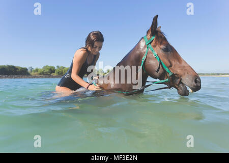 L'INDONÉSIE, Bali, femme assise sur le cheval dans l'eau Banque D'Images