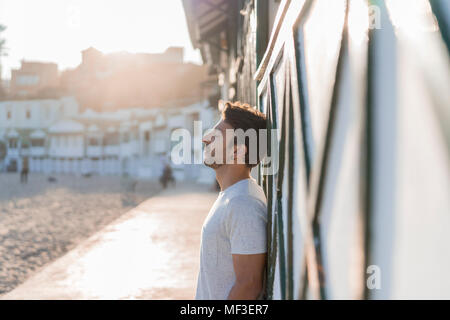 Jeune homme détente sur la plage au coucher du soleil Banque D'Images