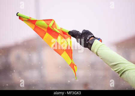 Arbitre de football soccer assistant soulève la drapeau. Arrière-plan de neige floue, vue en gros plan. Banque D'Images