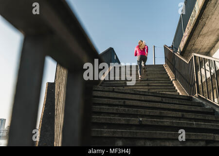 Young woman running up stairs Banque D'Images