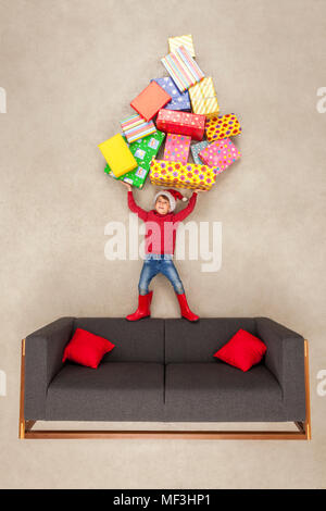 Boy with Santa hat holding pile de cadeaux de Noël Banque D'Images