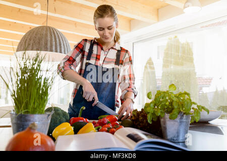 Femme enceinte dans la cuisine à couper le concombre Banque D'Images