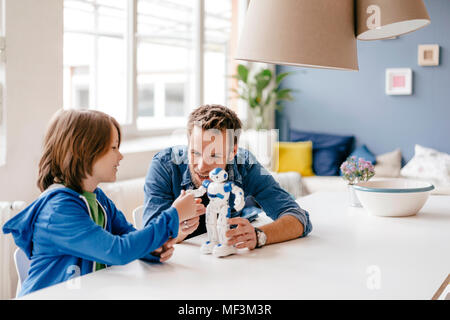 Heureux père et fils jouant avec robot sur la table à la maison Banque D'Images