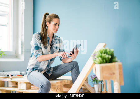 Remise à neuf femme sa nouvelle maison avec des palettes, using digital tablet Banque D'Images