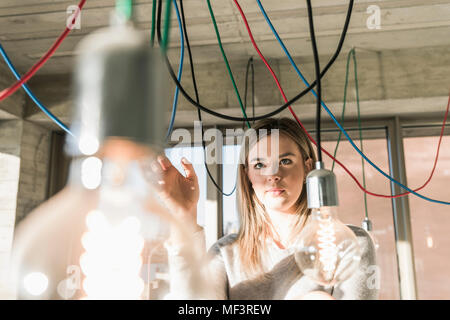 Young businesswoman in office d'examiner les câbles au niveau des ampoules Banque D'Images