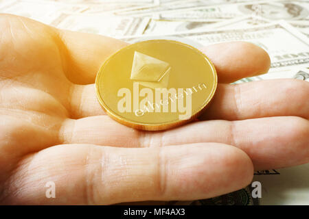 La main est holding coin ethereum ETH dans dollar billets. Cryptocurrency l'exploitation minière. Banque D'Images