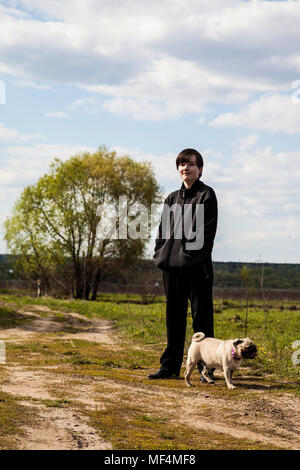 Adolescent promenades avec un chien sur le chemin d'un jour de printemps. Banque D'Images