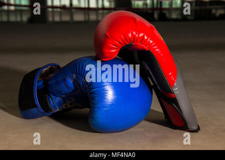 Gant de boxe rouge et bleu sur le ring de boxe dans une salle de sport, salle de remise en forme Banque D'Images