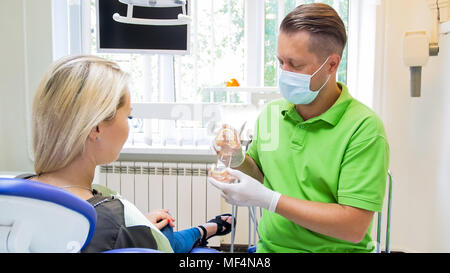 Dentiste à l'aide de la mâchoire mâle en plastique modèle pour expliquer à son patient de traitement Banque D'Images