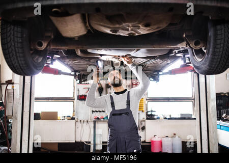 Homme mechanic repairing une voiture dans un garage. Banque D'Images