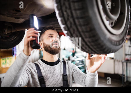 Homme mechanic repairing une voiture dans un garage. Banque D'Images