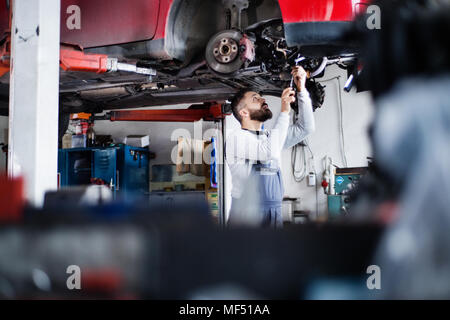 Homme mechanic repairing une voiture dans un garage. Banque D'Images