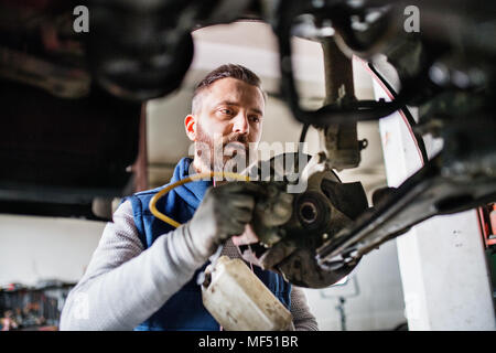 Homme mechanic repairing une voiture dans un garage. Banque D'Images