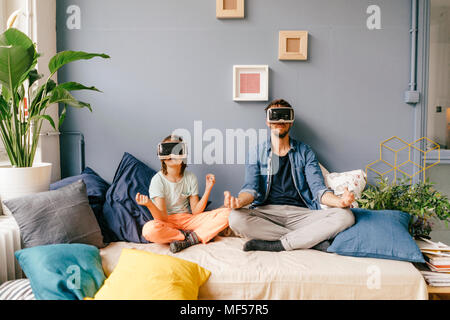 Père et fils portant des lunettes VR pratique le yoga à la maison Banque D'Images