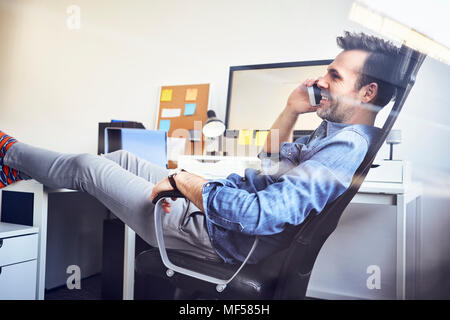 Ambiance man sitting at desk in office talking on cell phone