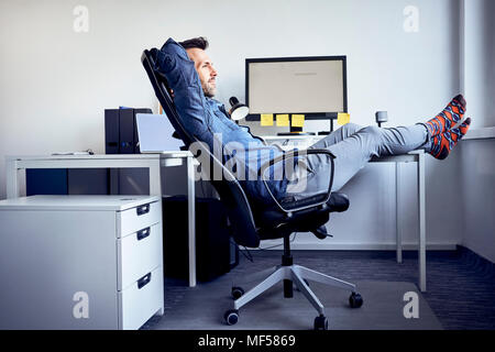 Man sitting at desk in office relaxing Banque D'Images