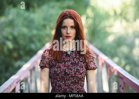 Portrait de jeune femme rousse debout sur la passerelle dans la nature Banque D'Images