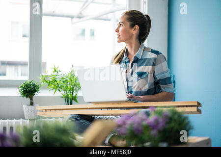 Remise à neuf femme sa nouvelle maison avec des palettes, using laptop Banque D'Images