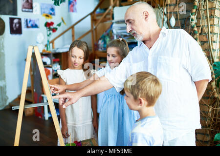 Professeur d'Art Mûr travaillant avec les enfants Banque D'Images