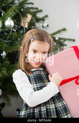 Portrait of smiling little girl holding Christmas present Banque D'Images