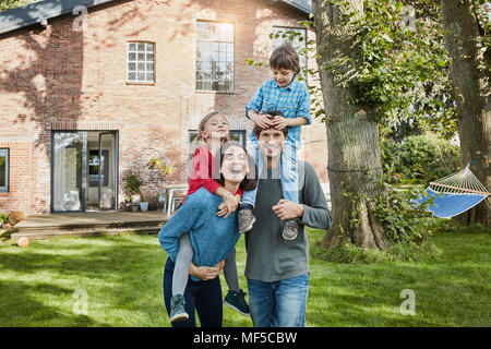 Portrait de famille heureuse dans le jardin de leur maison Banque D'Images