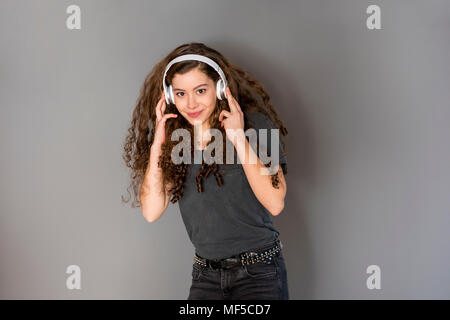 Portrait of teenage girl avec des cheveux bouclés à l'écoute de la musique avec des écouteurs Banque D'Images