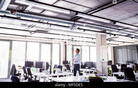 Businessman standing in open plan office Banque D'Images