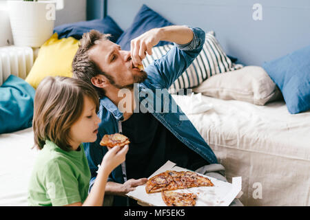 Père et fils de manger une pizza à la maison Banque D'Images