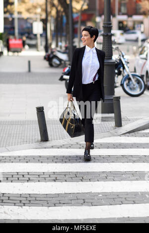 Smiling young woman crossing street Banque D'Images