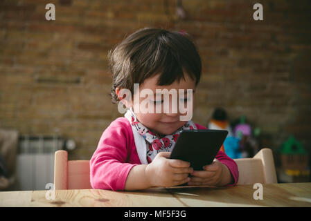 Baby Girl using mobile phone at home Banque D'Images