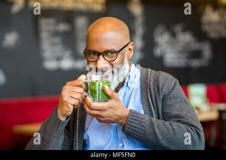 Portrait of smiling man avec verre de thé dans un café Banque D'Images