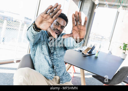 Portrait of smiling businessman in office qui fait un doigt frame Banque D'Images