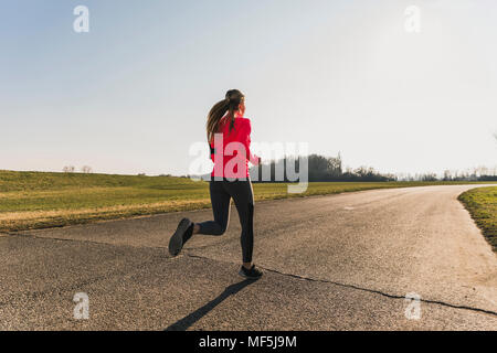 Young woman running on country road Banque D'Images