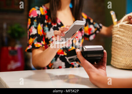 Close-up of woman with smartphone sans numéraire au comptoir d'un magasin Banque D'Images