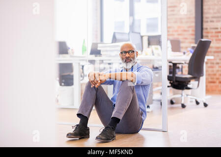 Portrait of businessman assis sur le plancher d'un bureau Banque D'Images