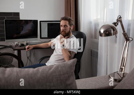 Portrait d'homme barbu assis dans le salon d'écouter la musique avec vos écouteurs Banque D'Images