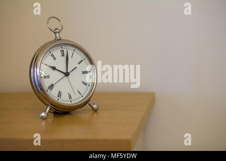 Tableau blanc fer horloge d'un plateau en bois contre un mur blanc. Banque D'Images